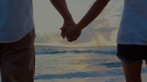 Couple holding hands at the beach to represent relationship therapy